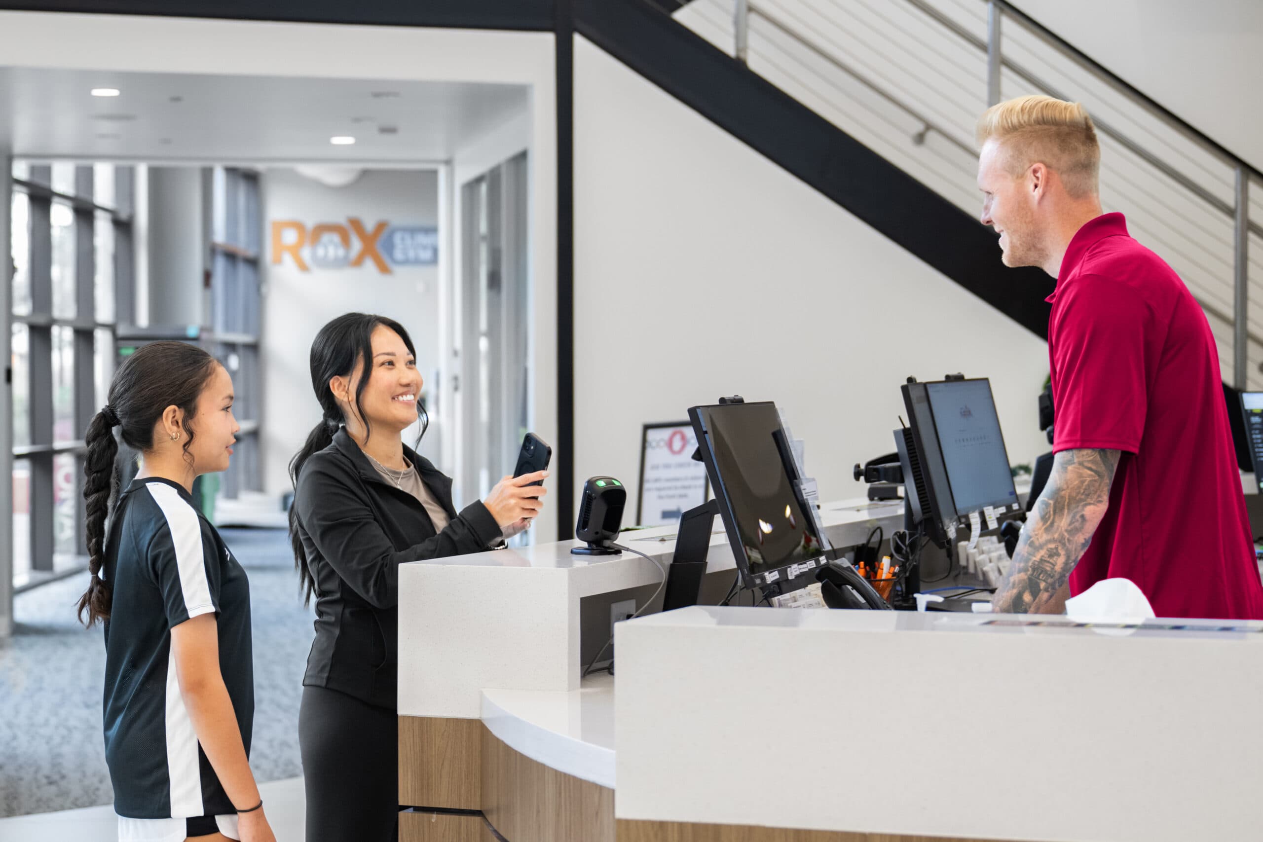 Front desk staff at a nonprofit community center managing peak season intake while assisting members at check-in.
