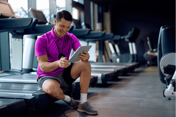 Fitness professional supporting a member’s wellness journey with digital tools and coaching inside a community organization