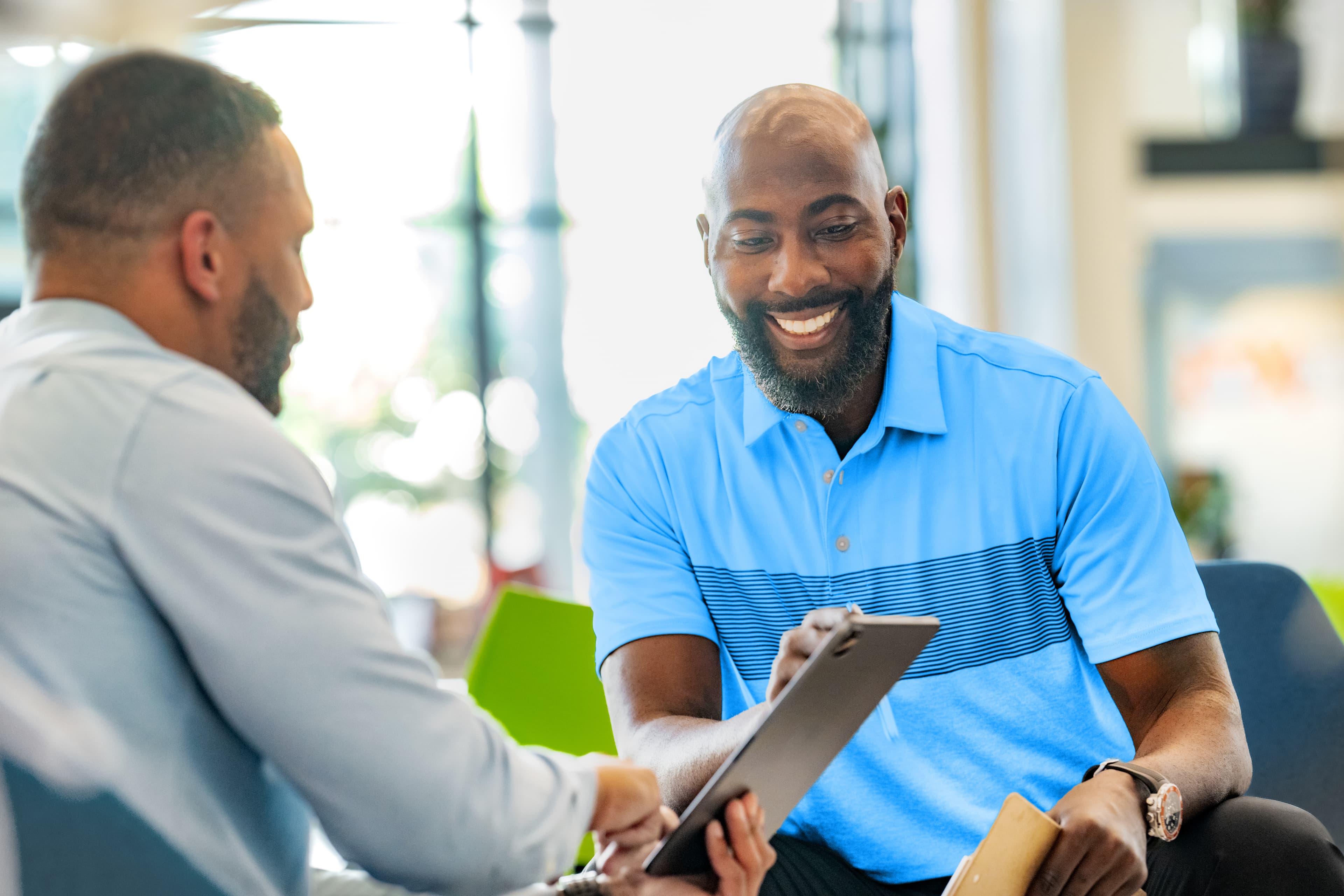Two men interacting and looking at a tablet together